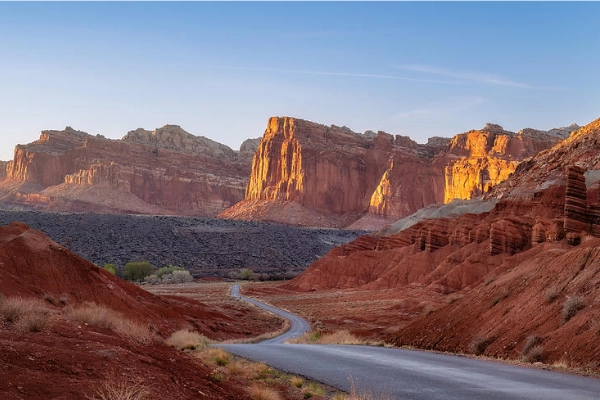 A car driving on the Scenic Drive surrounded by towering red cliffs