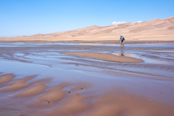 People enjoying the shallow waters of Medano Creek at the base of the dunes