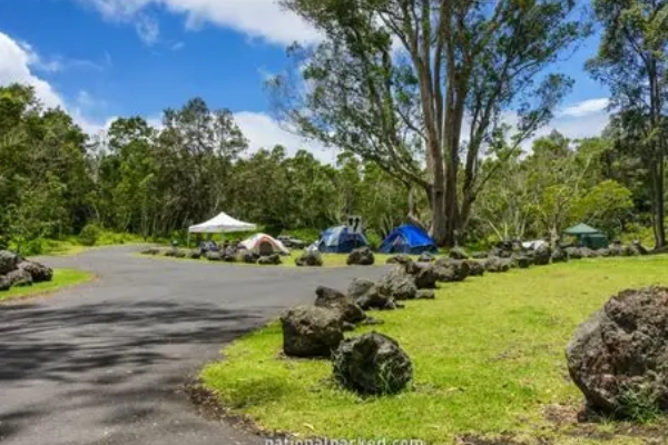 A tent at Namakanipaio Campground with the glow of lava on the horizon