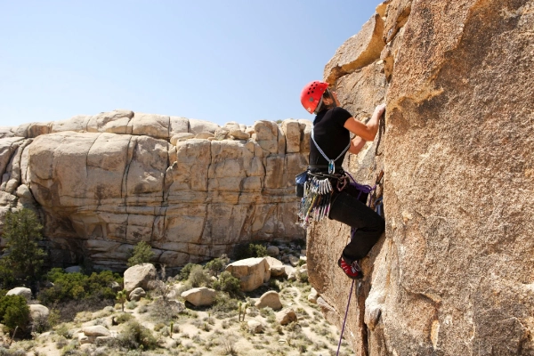 A rock climber scaling one of the giant boulders in Joshua Tree