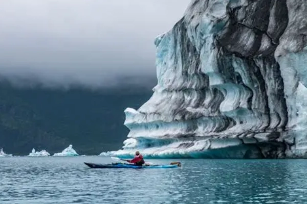 A sea kayaker paddling near a tidewater glacier