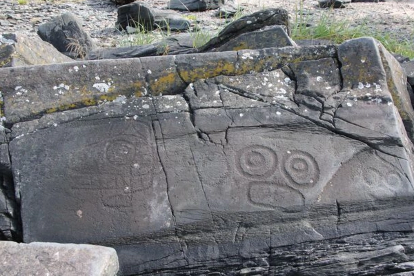 Ancient Inupiat petroglyphs carved into a rock near the dunes