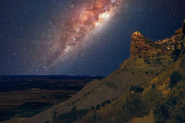 The Milky Way galaxy shining brightly in the dark sky above the mesa