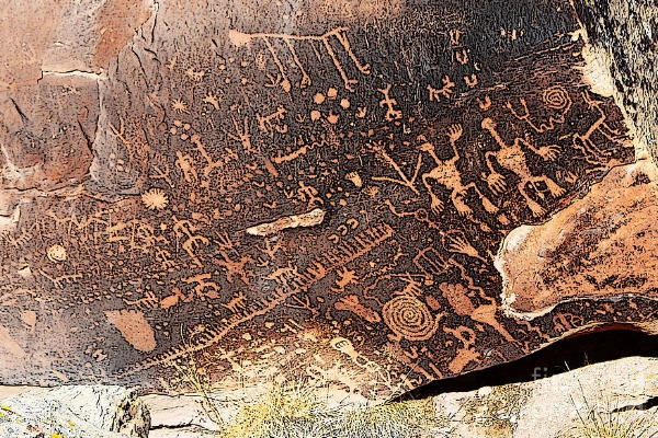 A large rock covered in ancient petroglyph carvings