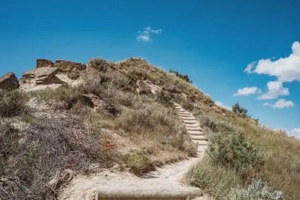 A painted rock marker with Native American symbols along a cliff trail