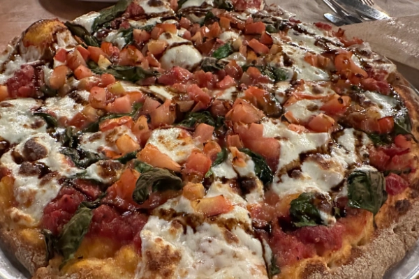 A slice of pizza with venison sausage and a frontier kick