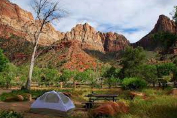 A tent set up at a riverside campground under a star-splashed sky